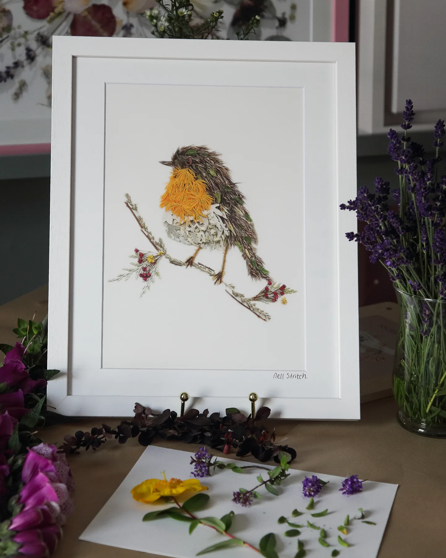 A pressed flower robin in a white frame