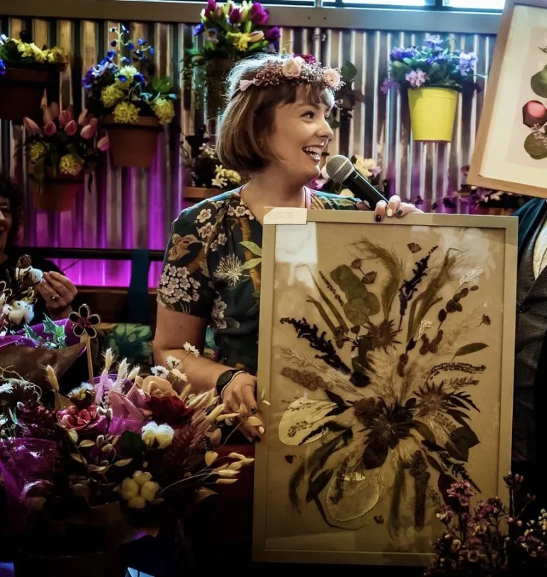 Nell speaking at an event beside a pressed flower piece