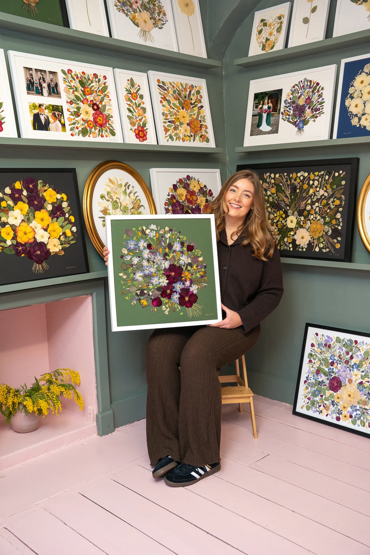 Nell in the studio holding a finished pressed bouquet on a green mountboard