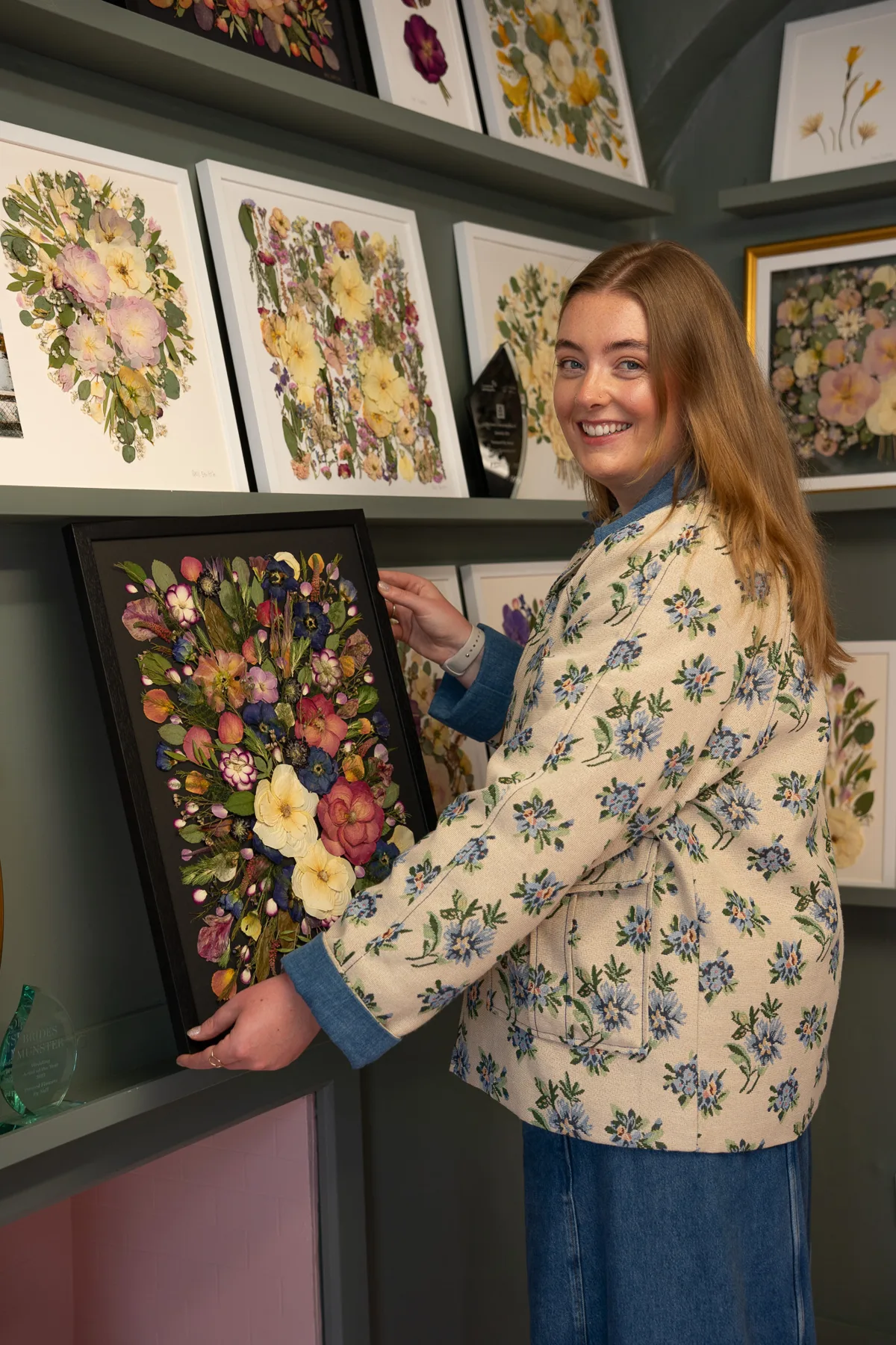 Nell holding a pressed bouquet on black, in front of the studio wall