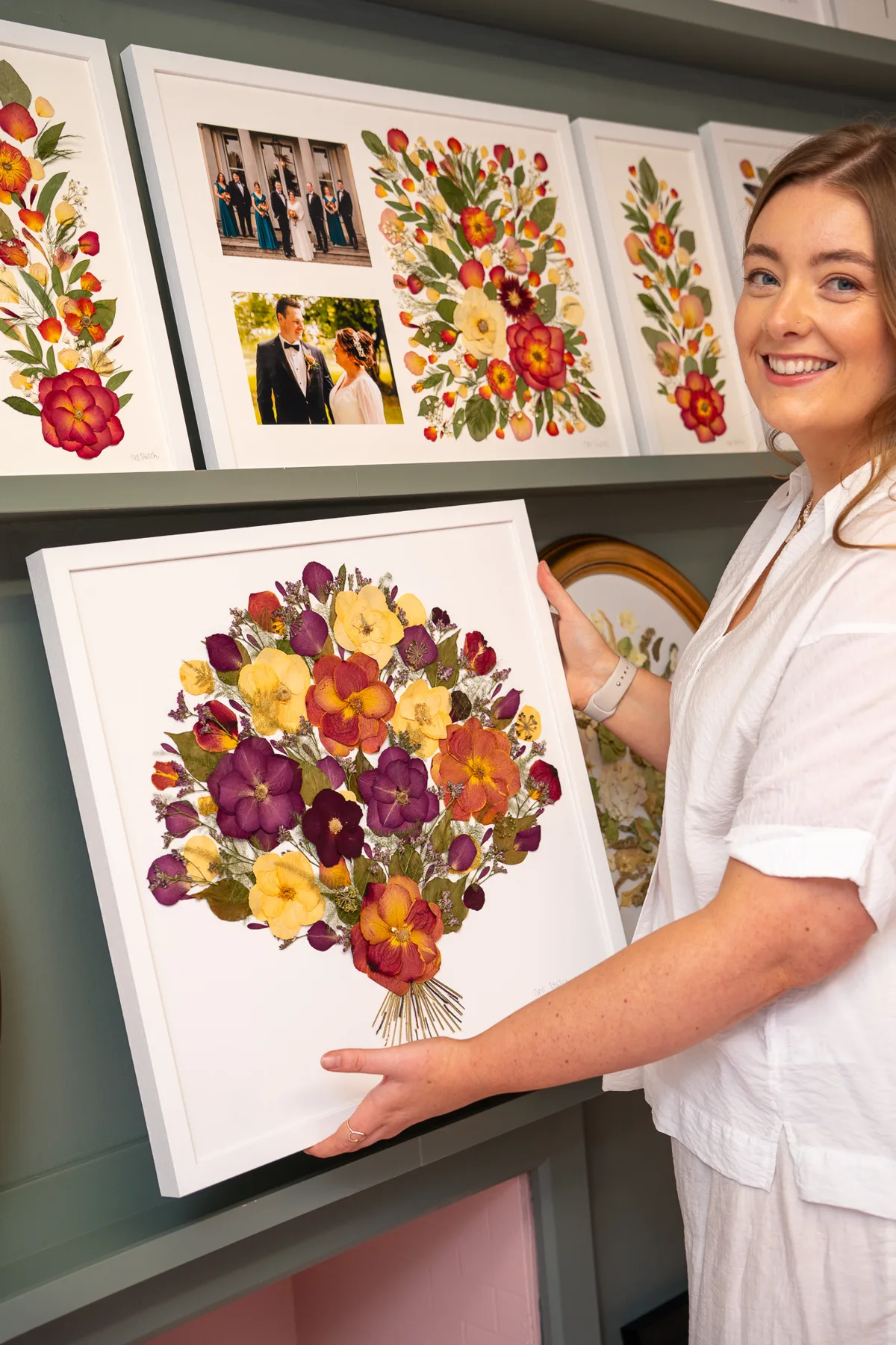 Nell smiling with a framed pressed bridal bouquet