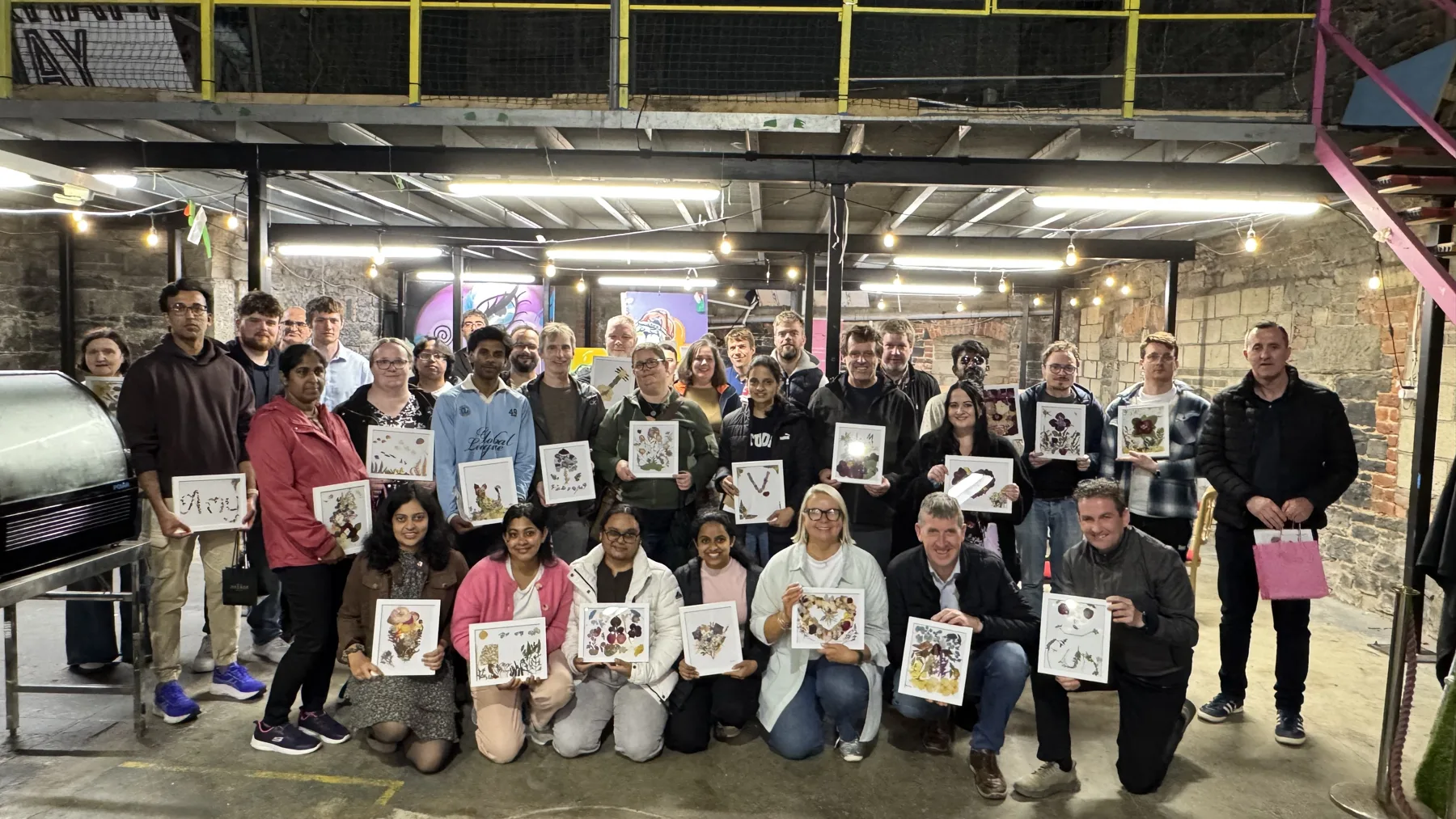 A corporate team holding the artwork they made at a workshop