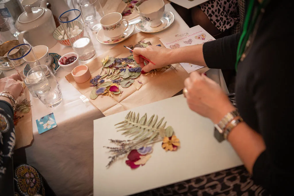 Hands placing pressed petals on a workshop artwork