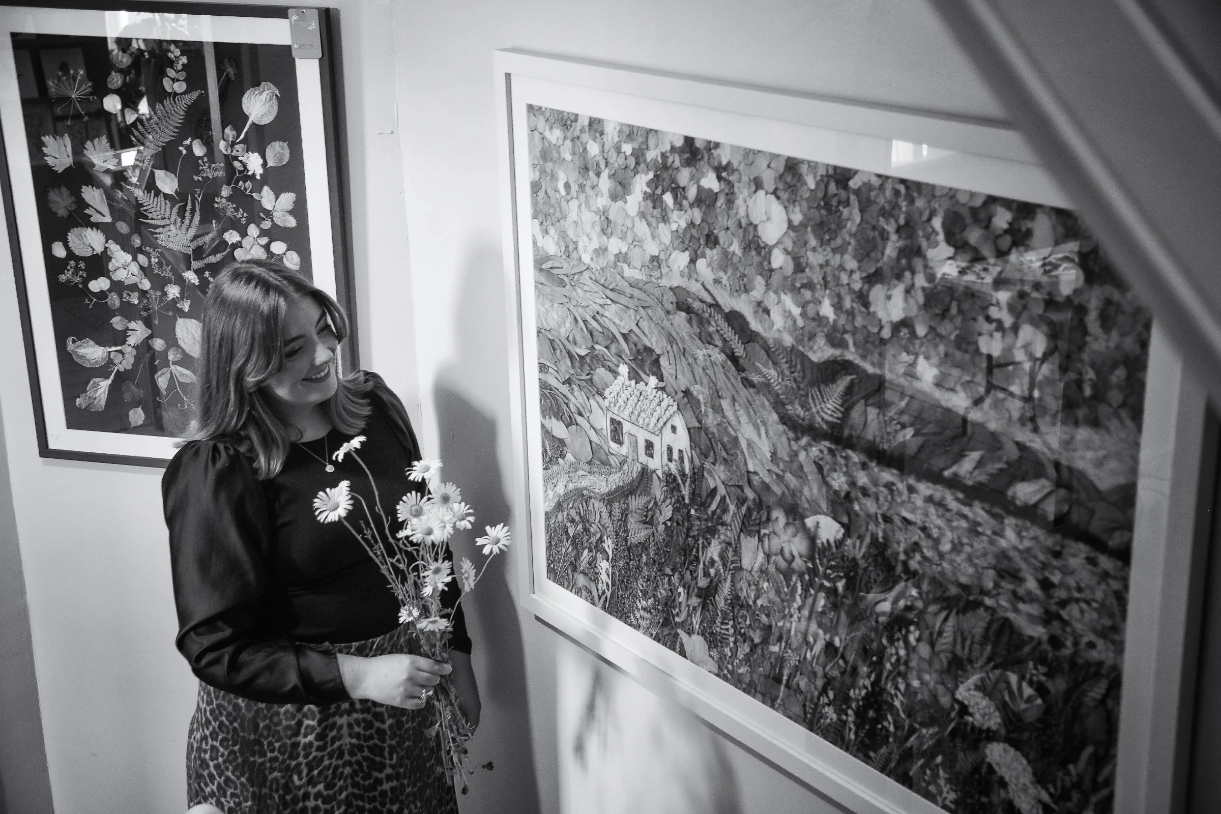 Nell smiling beside her framed pressed flower artwork