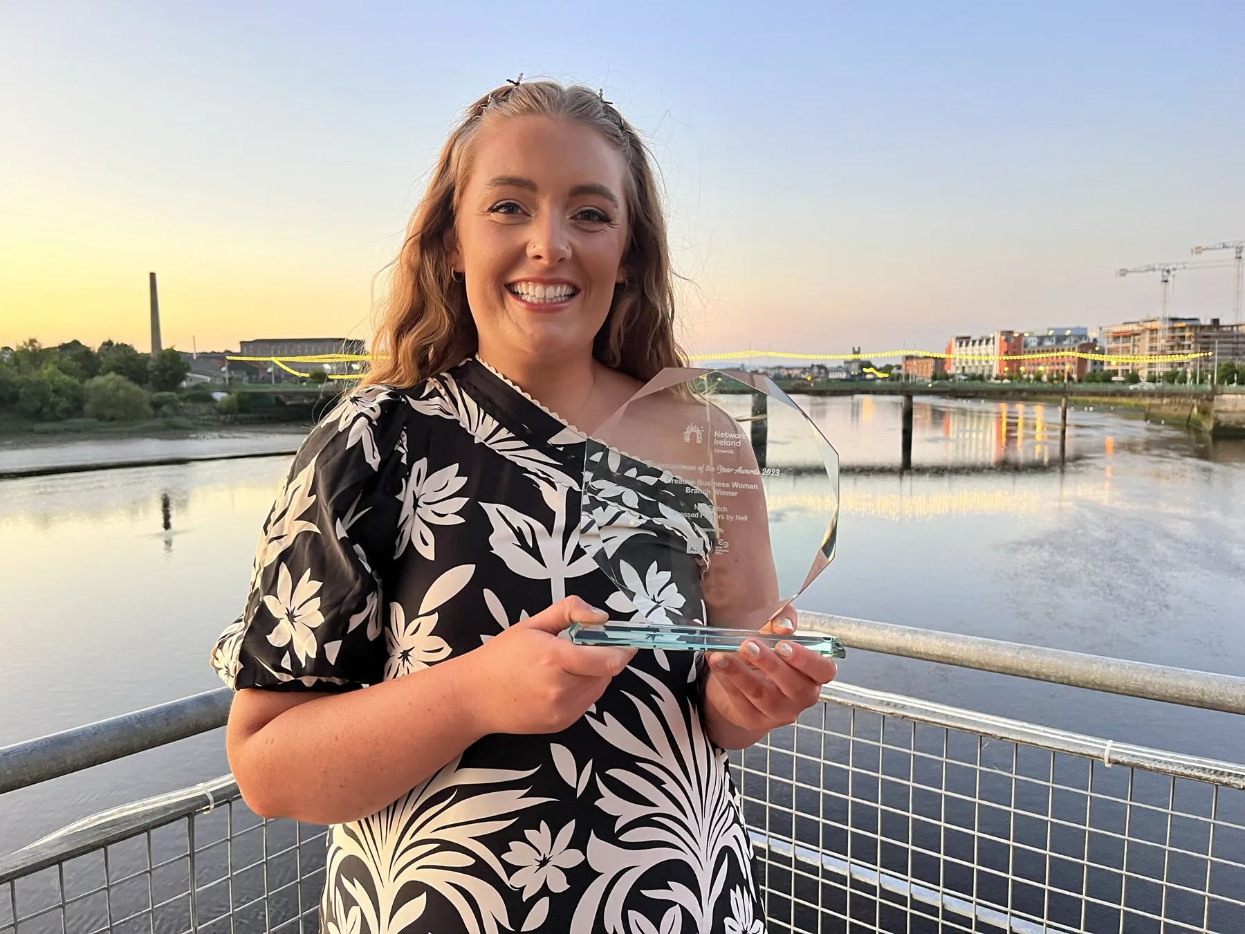 Nell holding her Creative Professional of the Year award by the river in Limerick