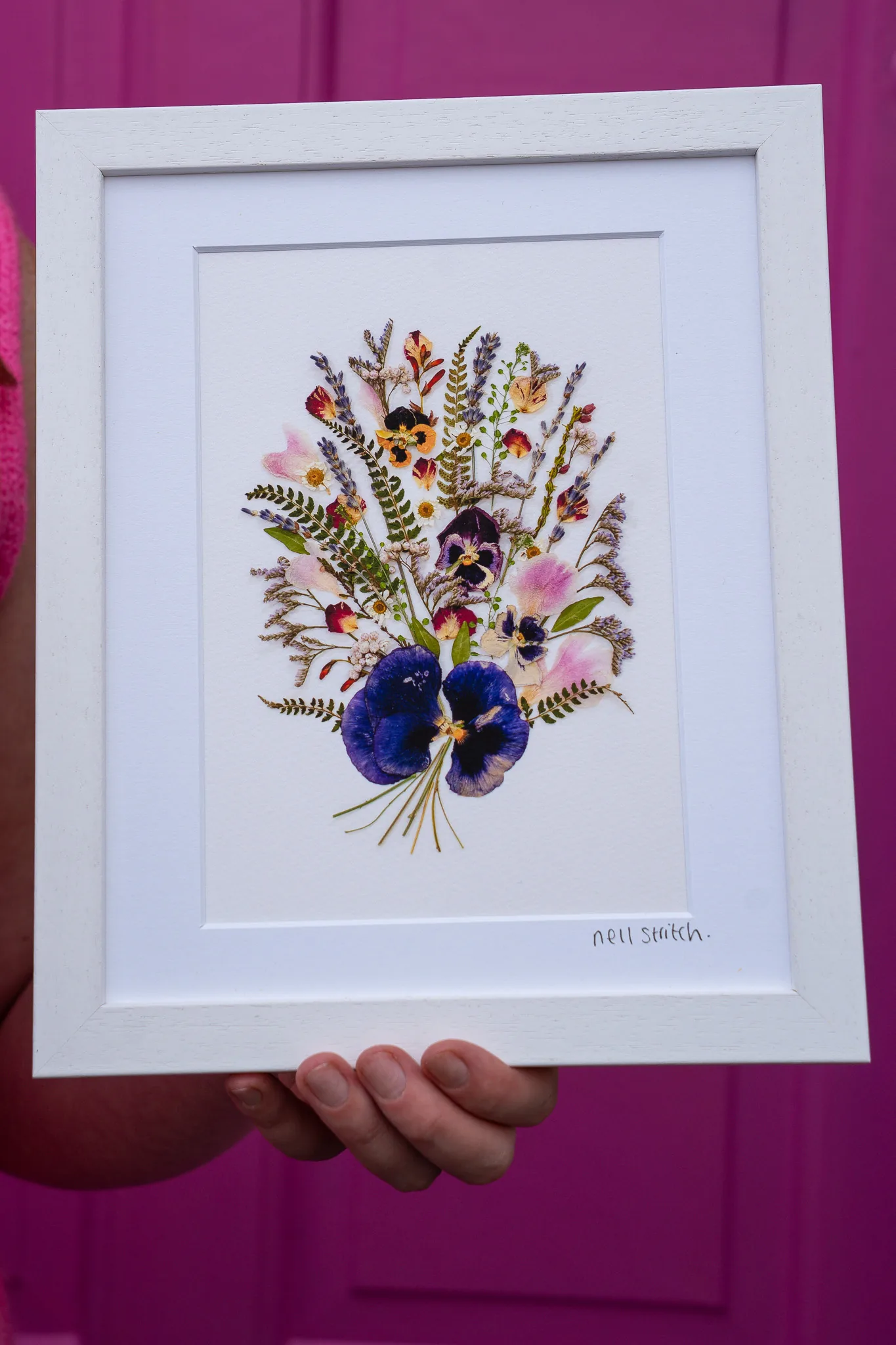 A framed pressed flower bouquet held in two hands