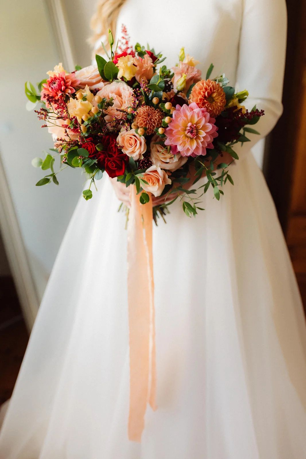 A bride by the window holding her wedding bouquet