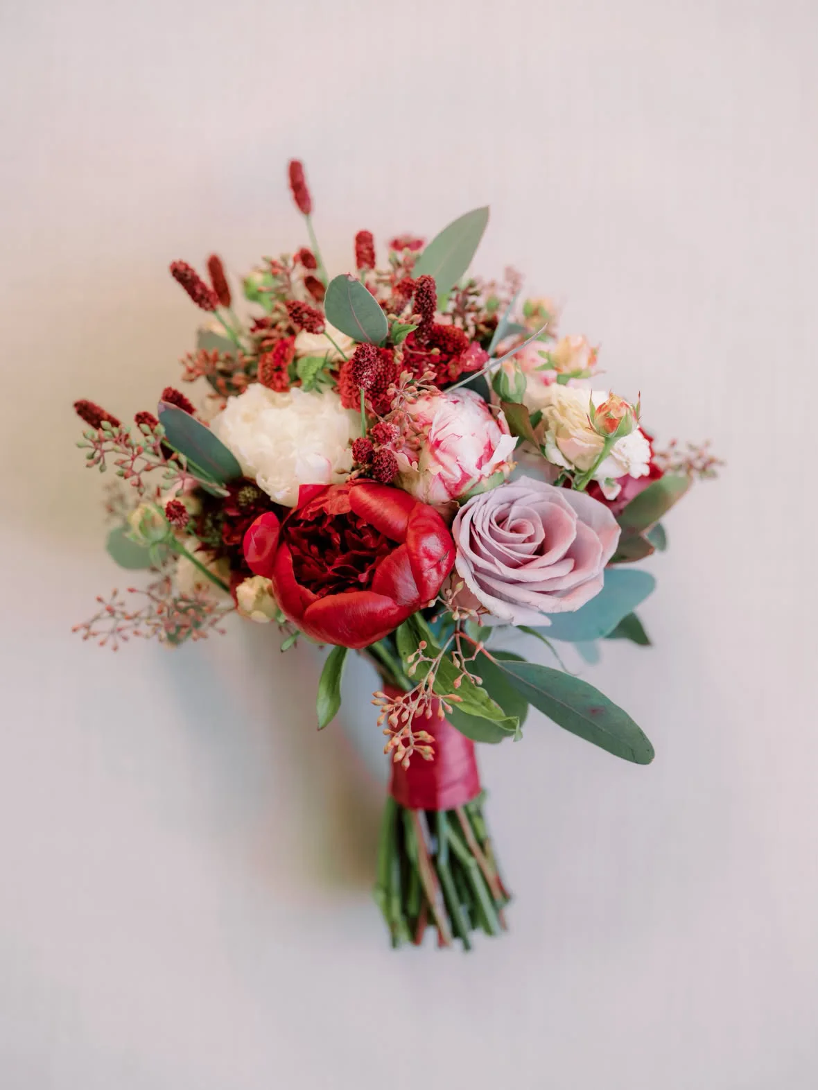 A bride in a white gown holding an orange and peach bouquet
