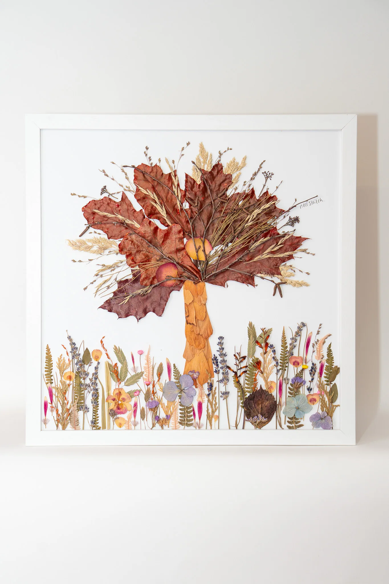 A pressed flower tree with autumn leaves in a white frame