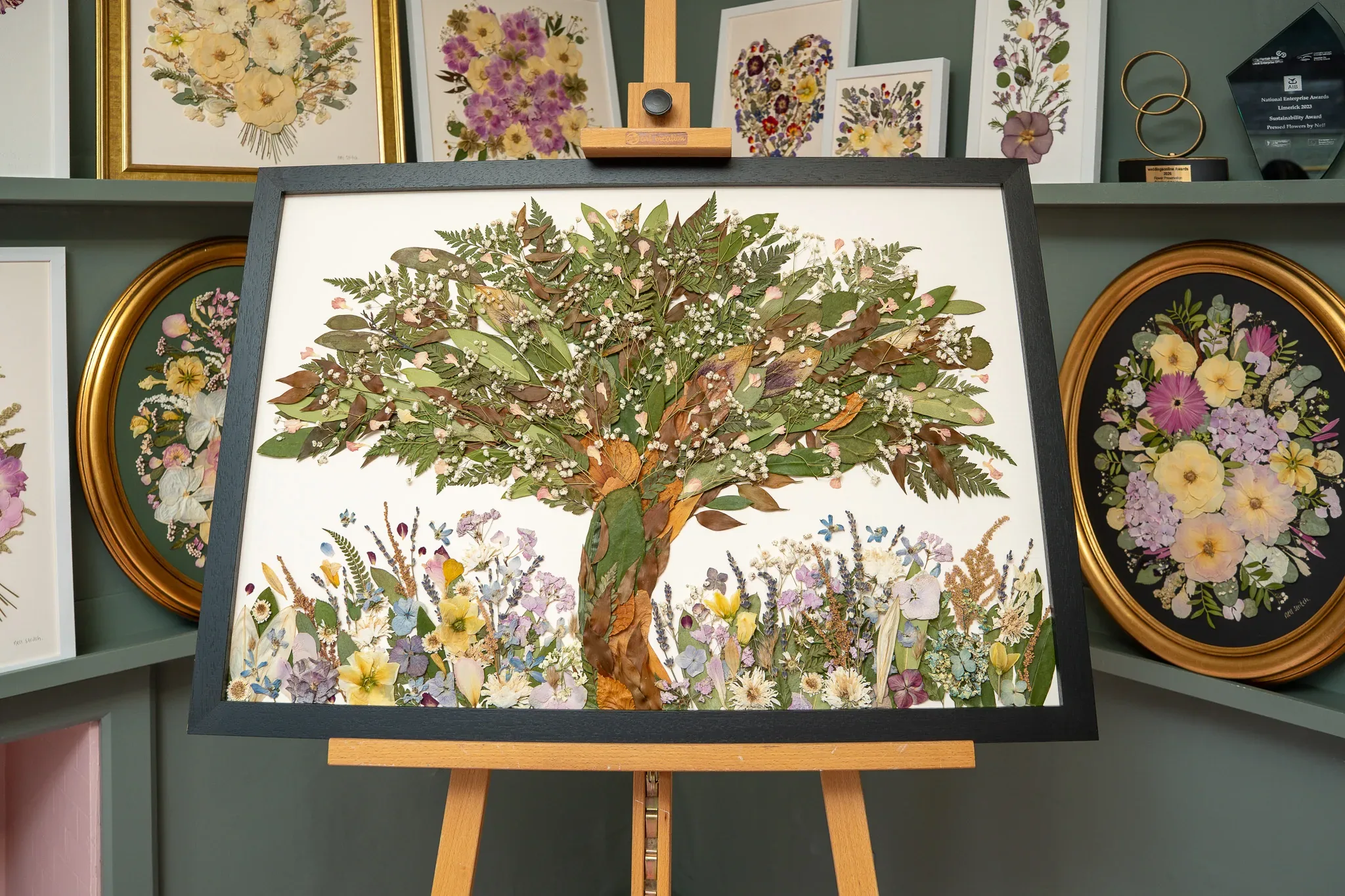 A pressed flower tree in a black frame on an easel