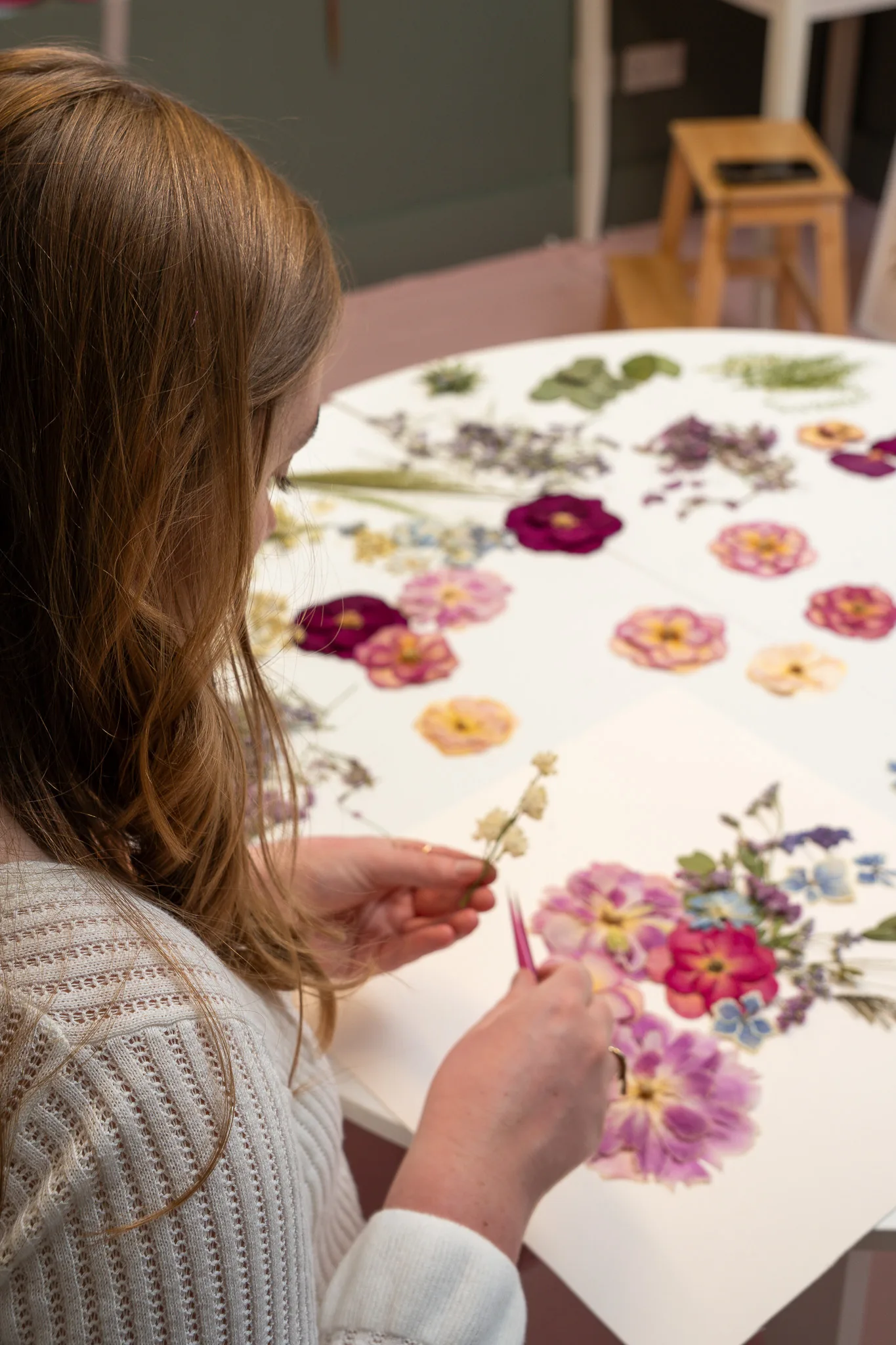 Nell arranging pressed flowers at the studio table