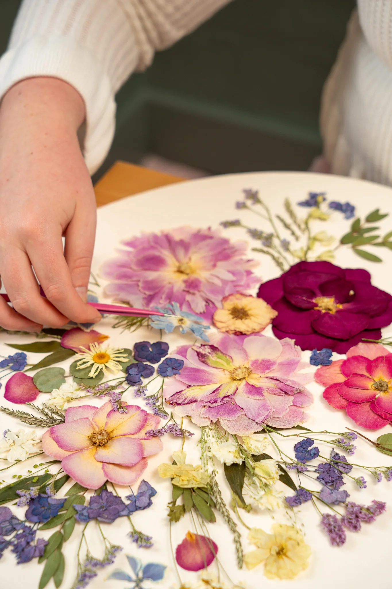 Nell arranging colourful pressed flowers on a round board