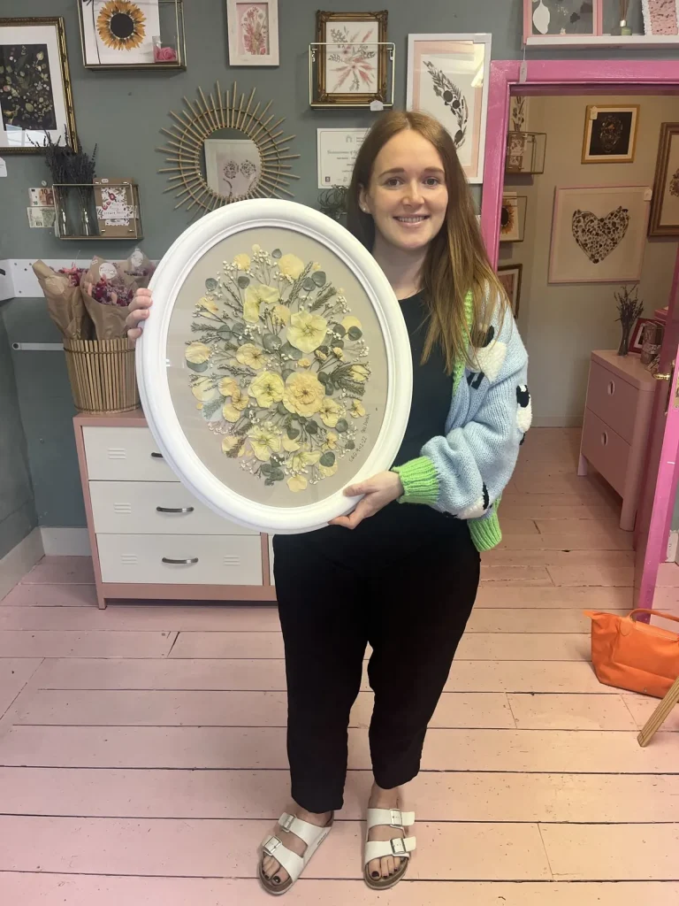 A happy bride with her framed pressed wedding bouquet
