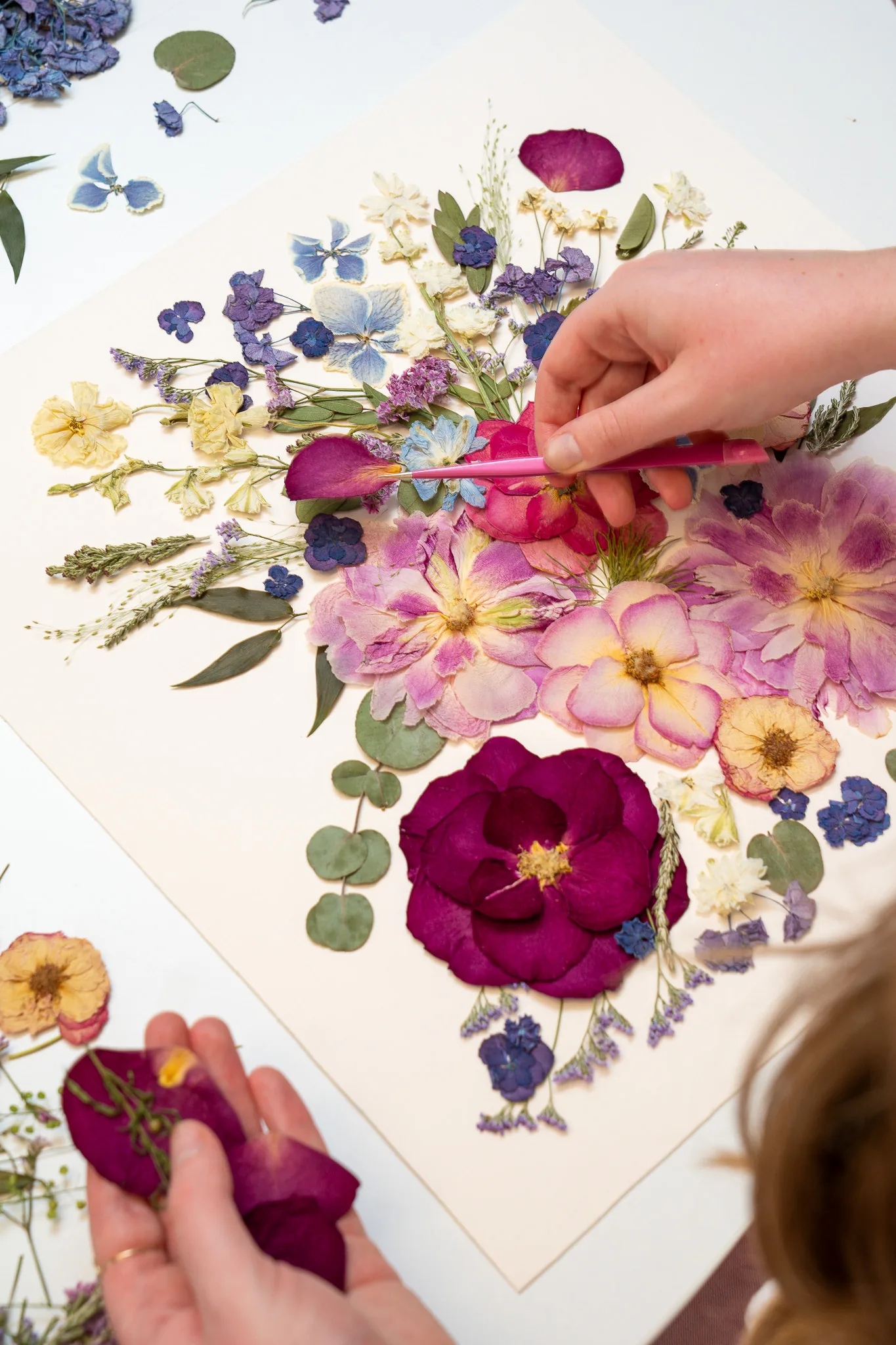 Nell’s hands arranging pressed wedding flowers into a bouquet design