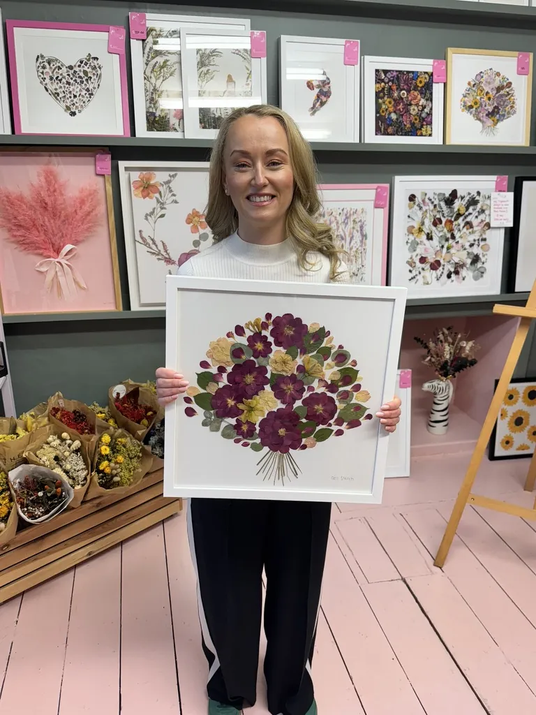 A happy customer with her pressed bouquet in a white frame