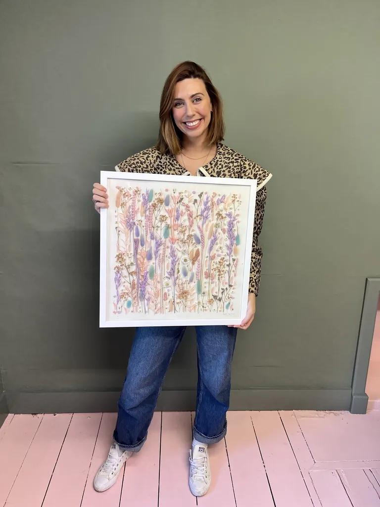 A happy bride with her framed pressed wedding bouquet