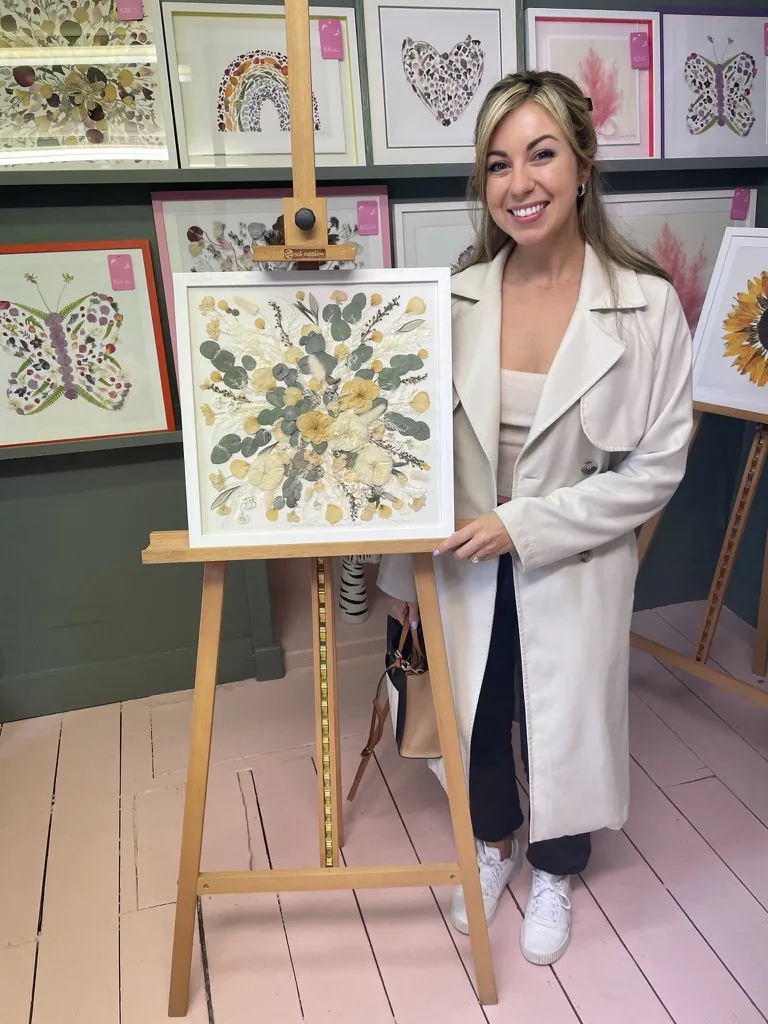 A customer with her pressed flower artwork on an easel