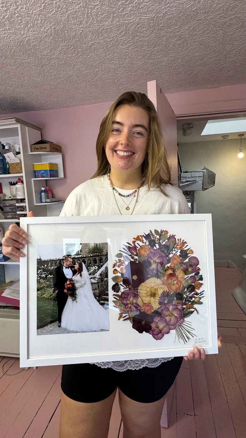 A happy bride with her framed pressed wedding bouquet