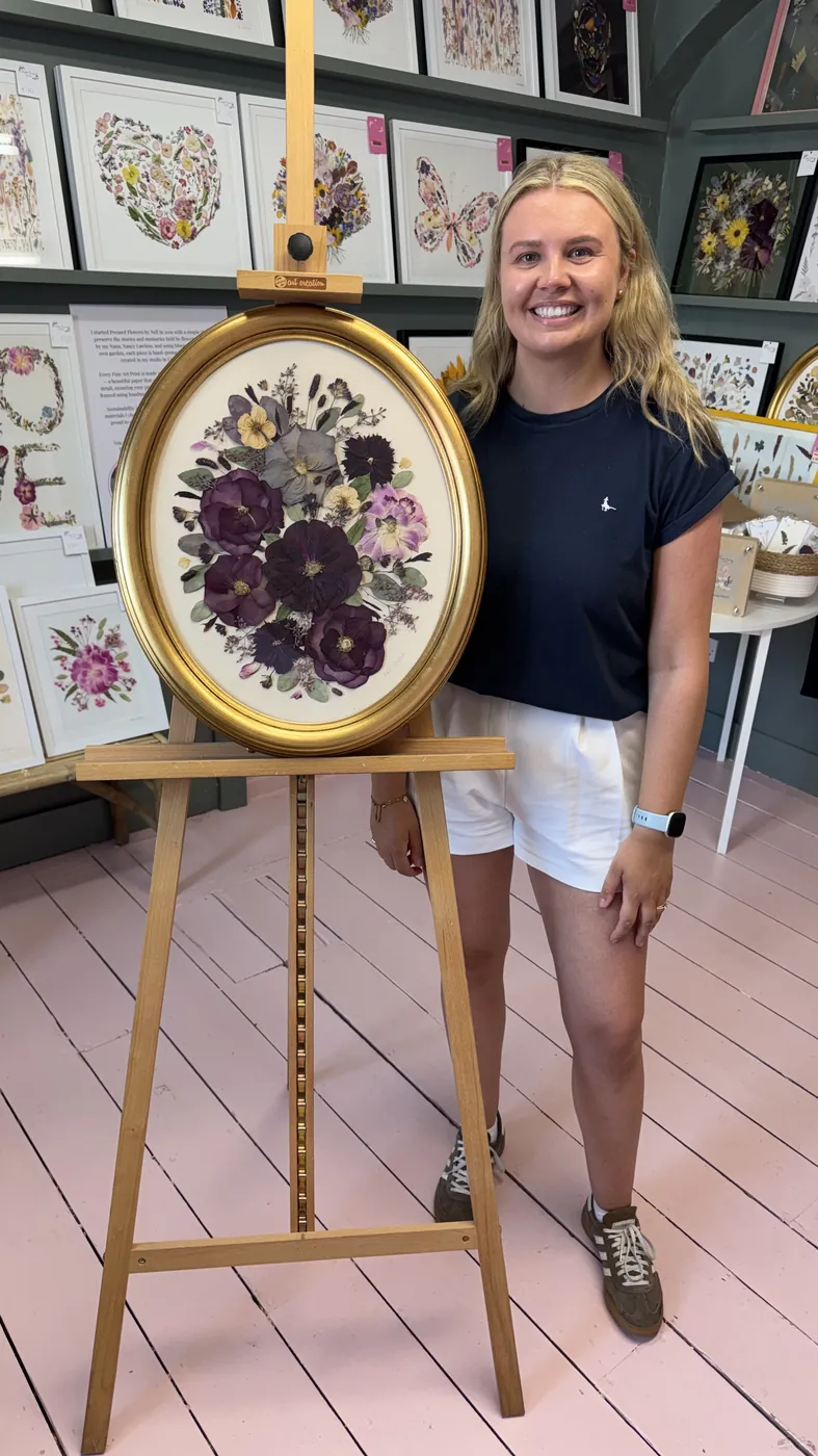A happy customer with a dark oval frame of pressed flowers