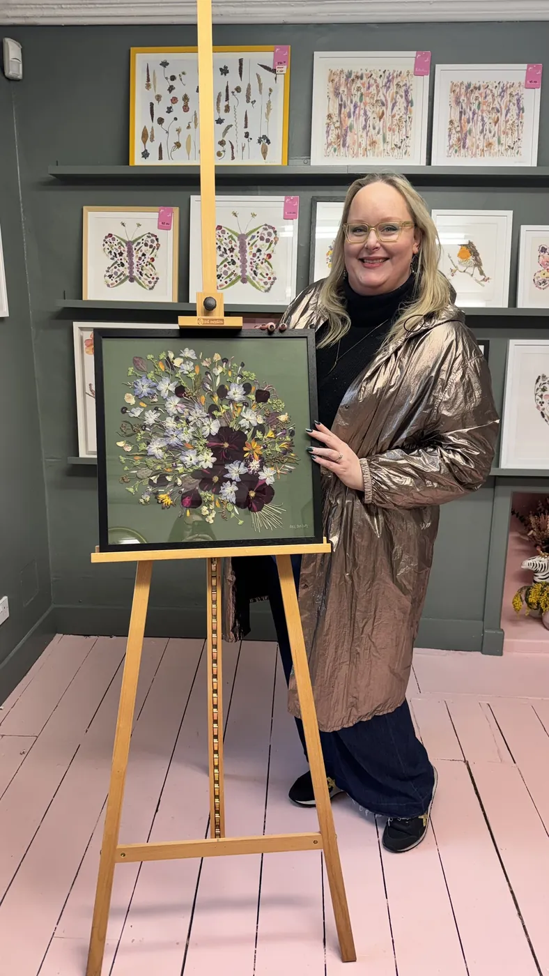 A happy bride with her framed pressed wedding bouquet