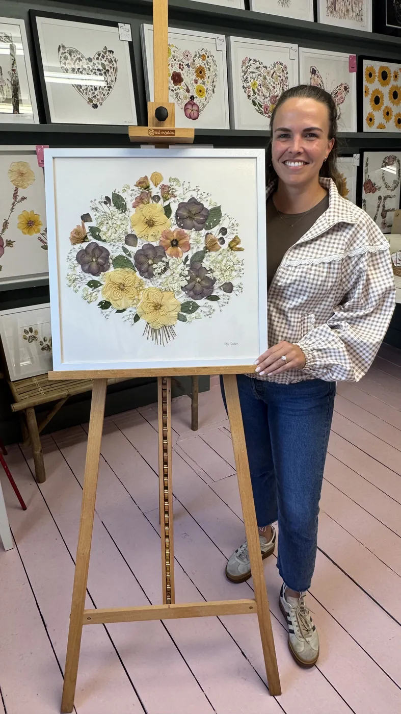 A happy bride with her framed pressed wedding bouquet
