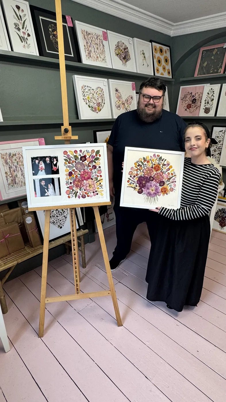 A happy bride with her framed pressed wedding bouquet
