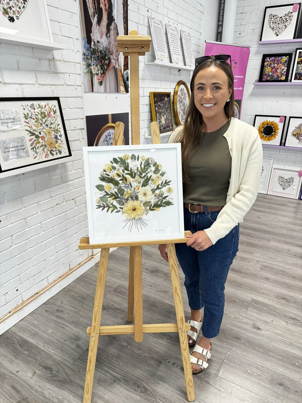 A happy bride with her framed pressed wedding bouquet