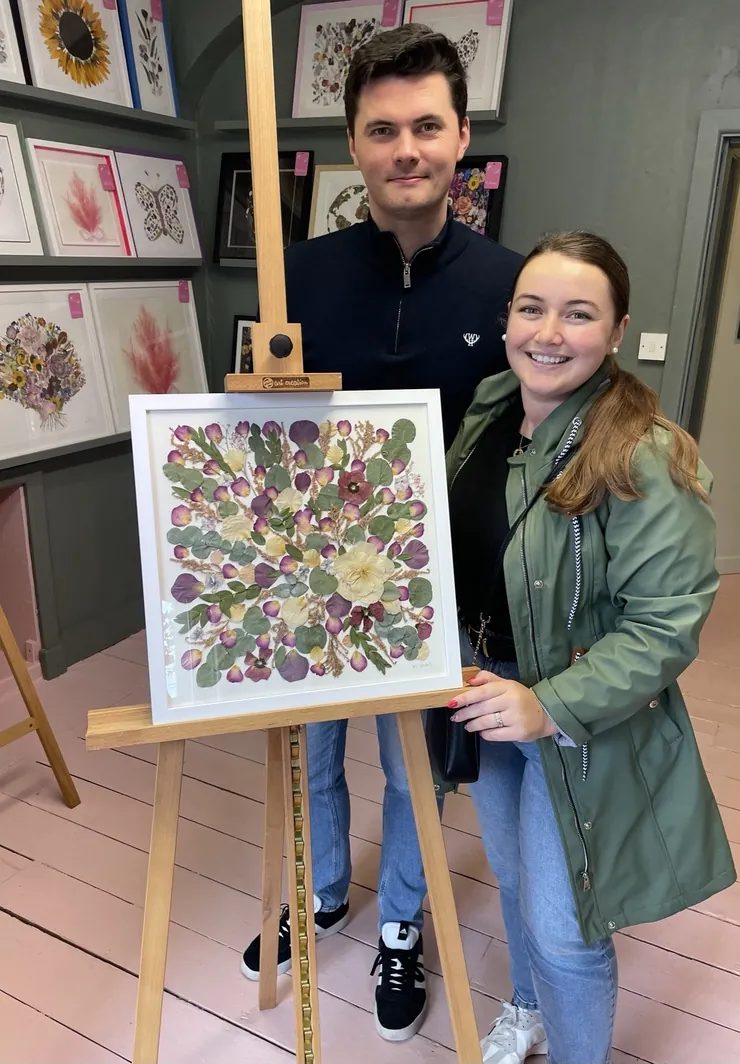 A happy bride with her framed pressed wedding bouquet
