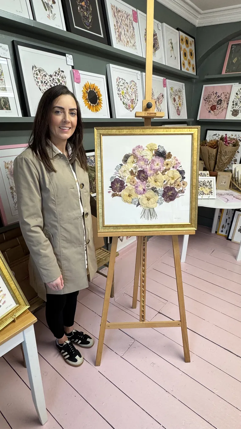 A happy bride with her framed pressed wedding bouquet