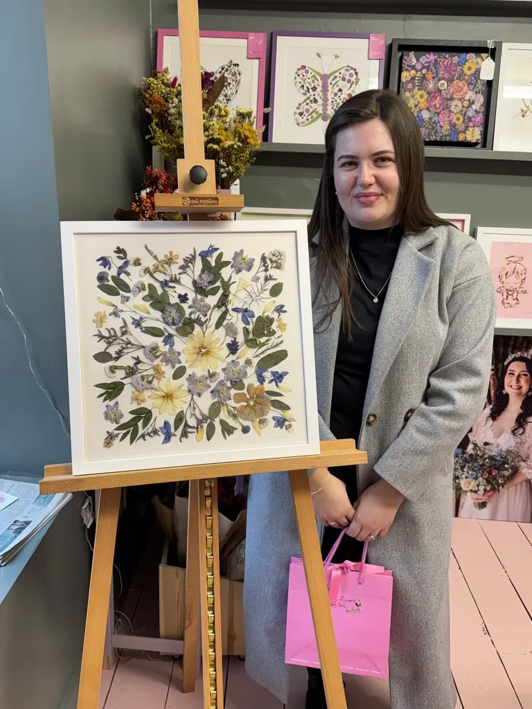A happy bride with her framed pressed wedding bouquet