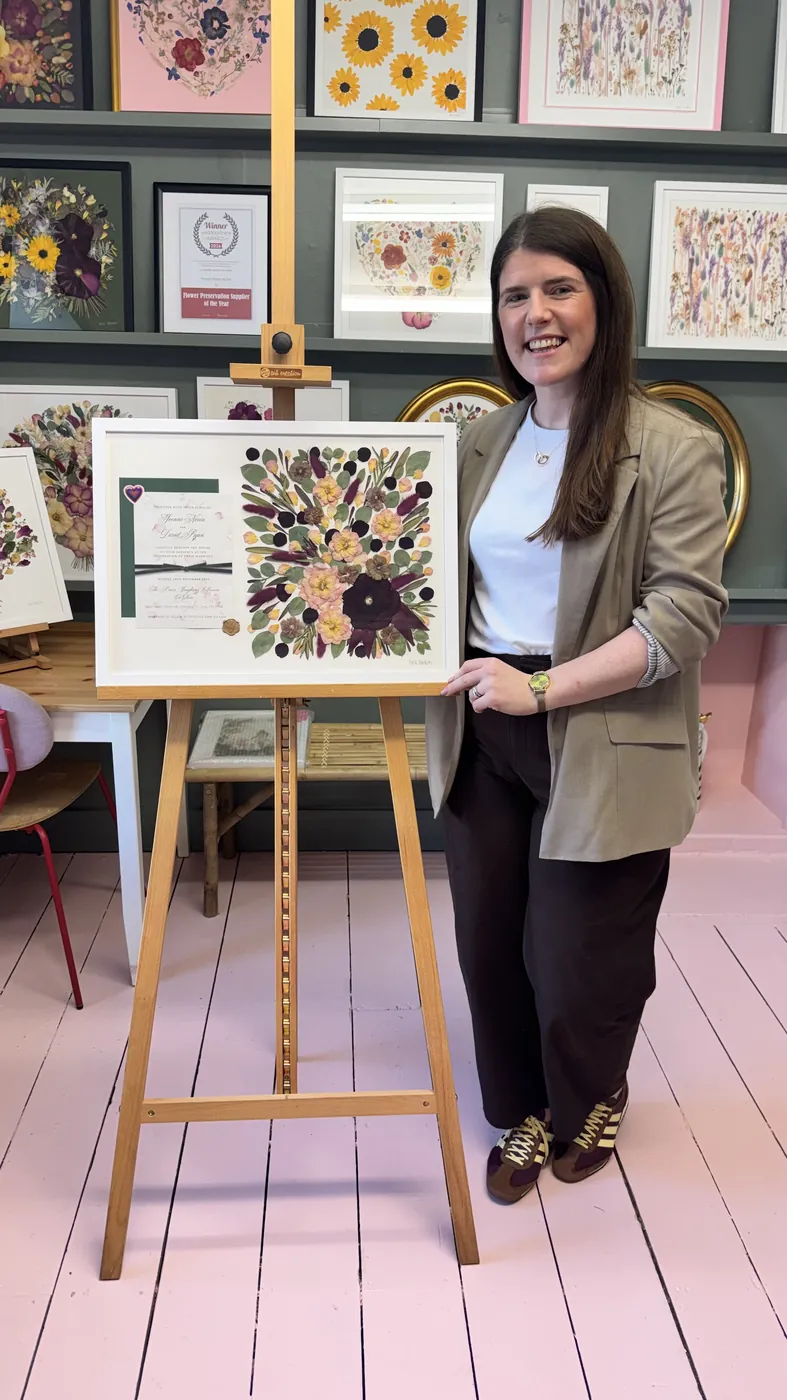 A happy bride with her framed pressed wedding bouquet