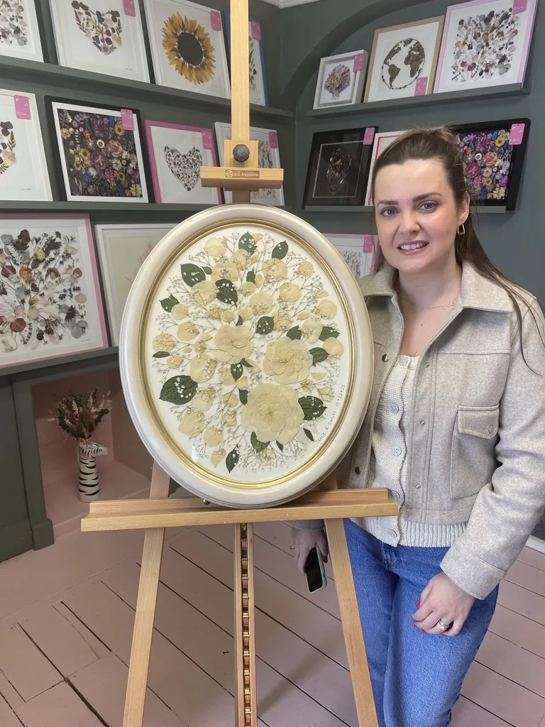 A happy bride with her framed pressed wedding bouquet