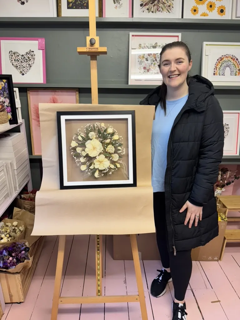 A happy bride with her framed pressed wedding bouquet