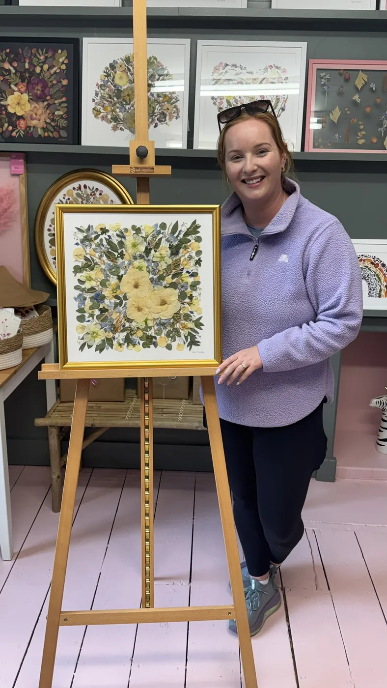 A happy bride with her framed pressed wedding bouquet
