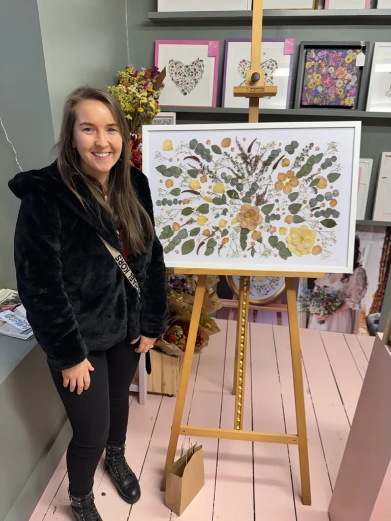 A happy bride with her framed pressed wedding bouquet