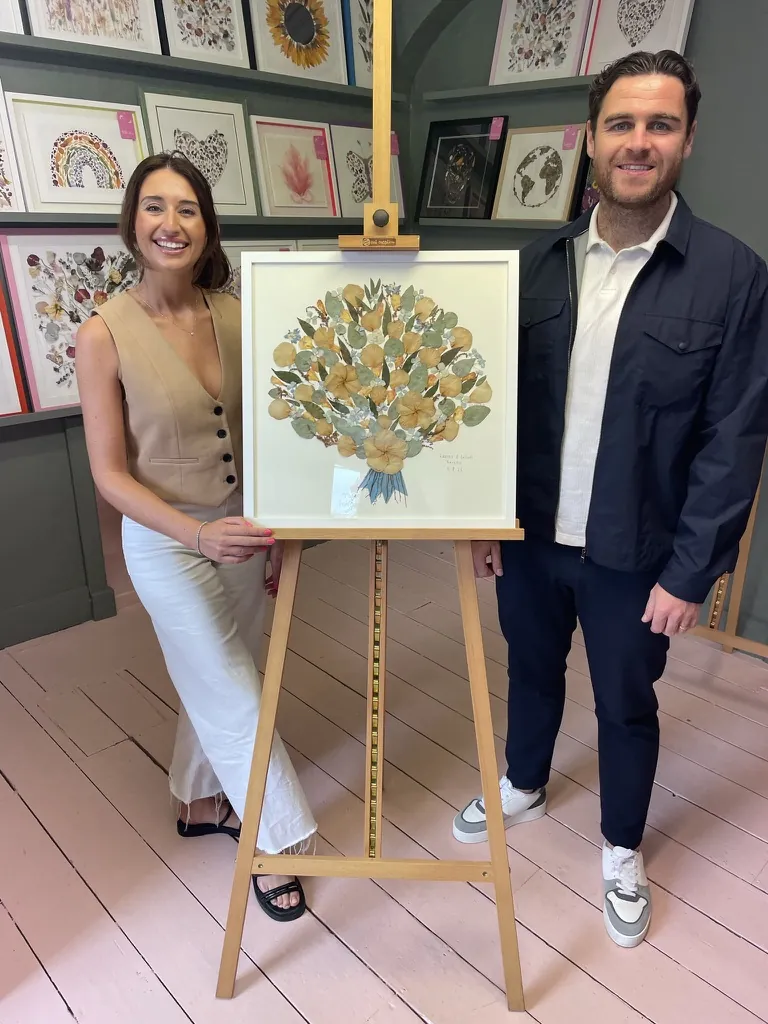 A happy bride with her framed pressed wedding bouquet