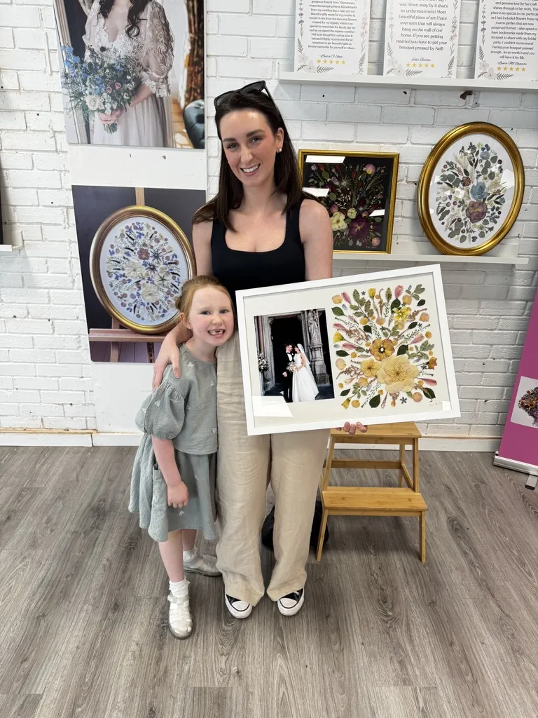 A happy bride with her framed pressed wedding bouquet