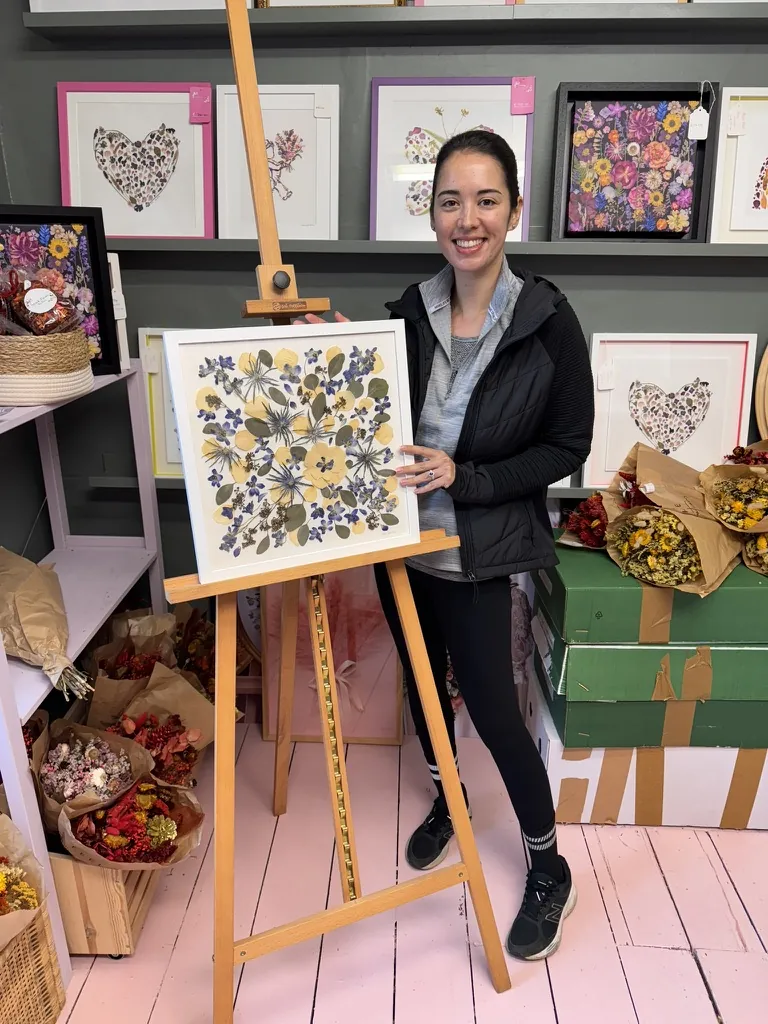 A happy bride with her framed pressed wedding bouquet