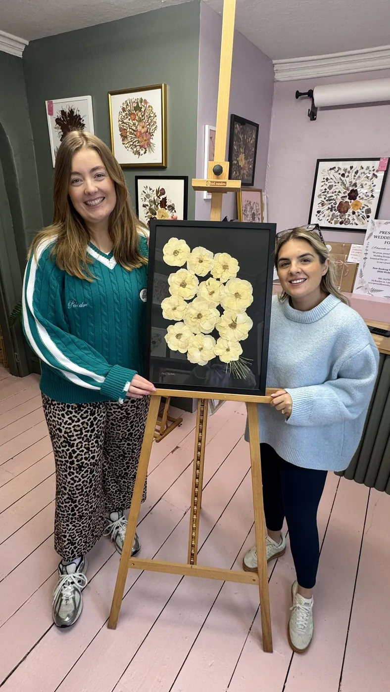 A happy bride with her framed pressed wedding bouquet