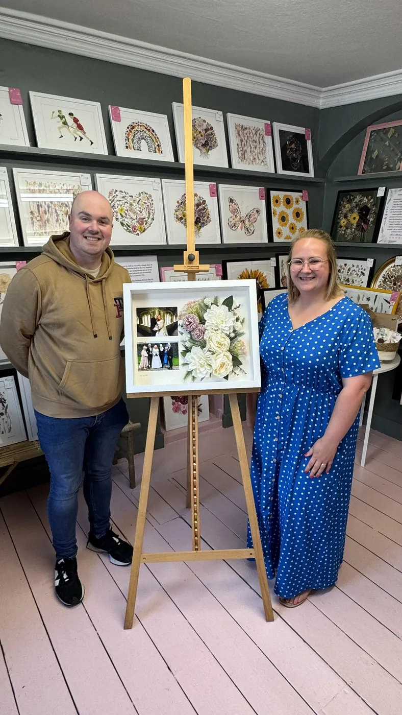 A happy bride with her framed pressed wedding bouquet