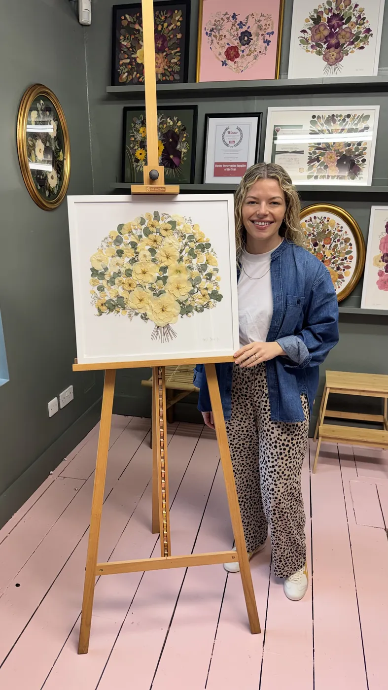 A happy bride with her framed pressed wedding bouquet