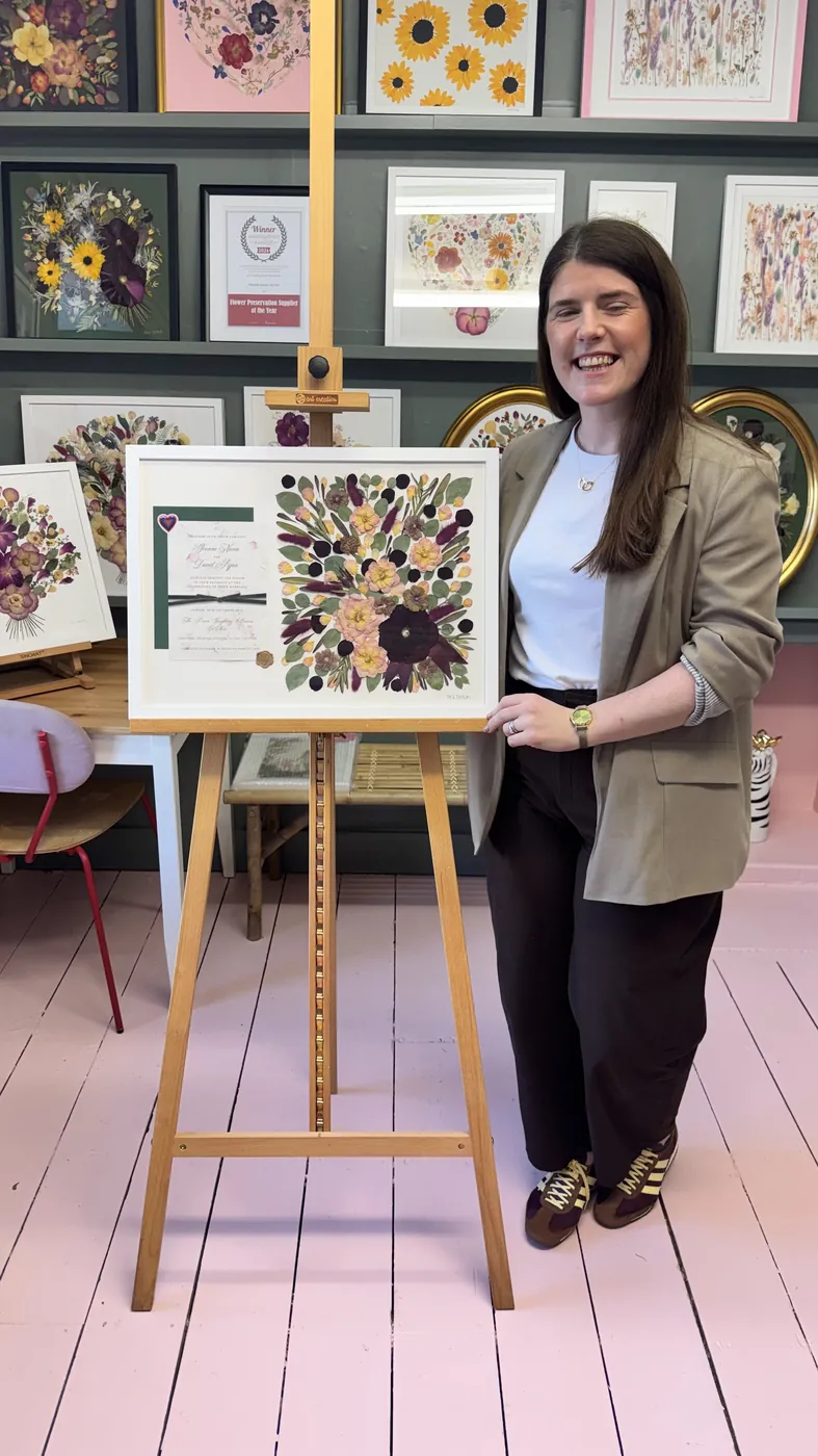 A happy bride with her framed pressed wedding bouquet