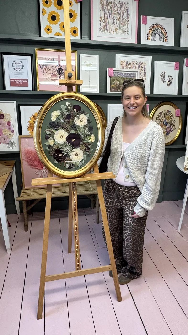 A happy bride with her framed pressed wedding bouquet