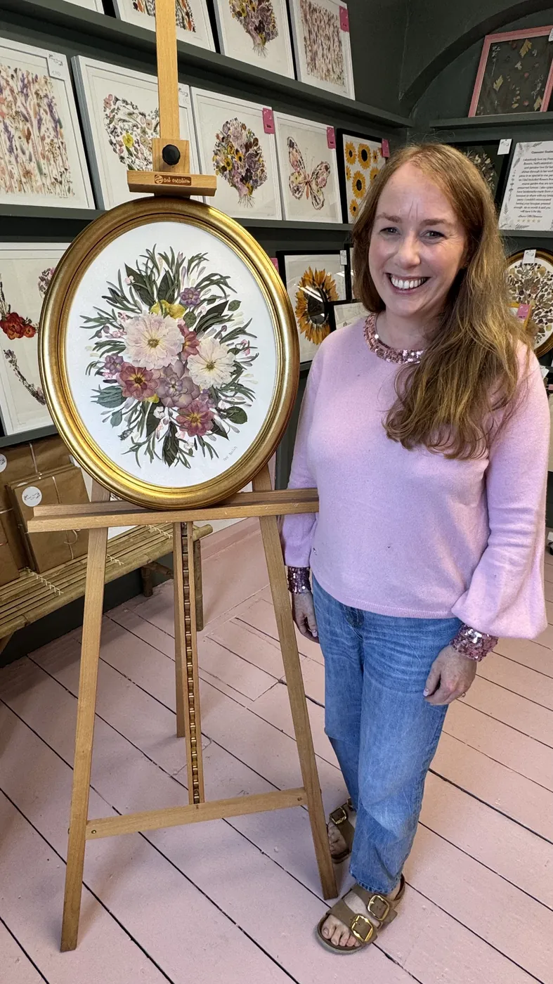 A happy bride with her framed pressed wedding bouquet