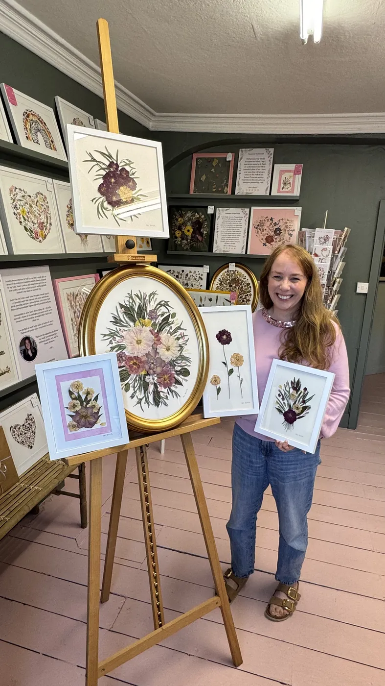 A happy bride with her framed pressed wedding bouquet