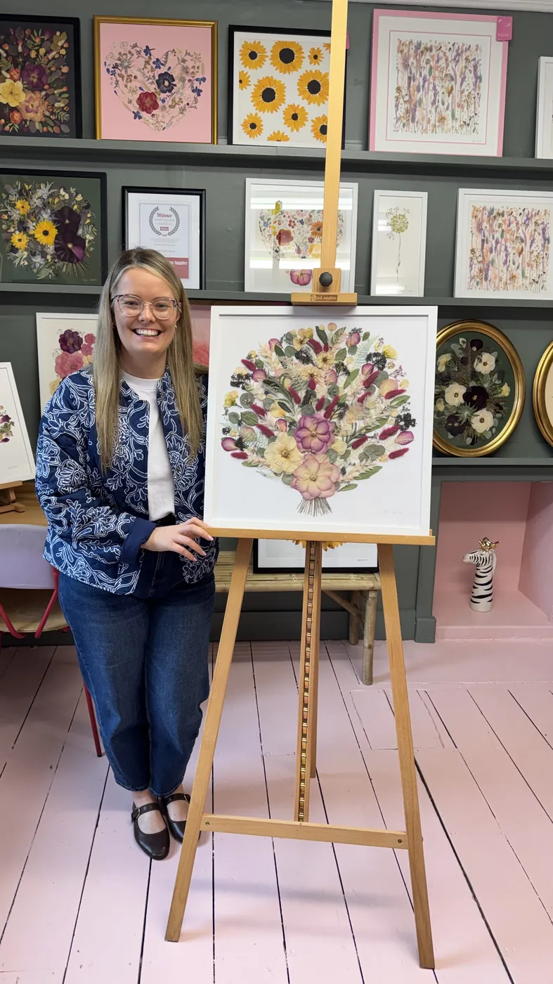 A happy bride with her framed pressed wedding bouquet