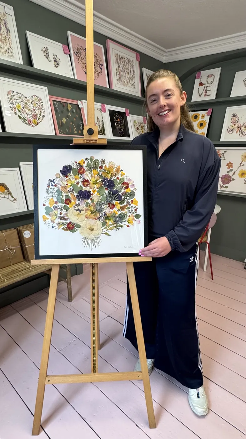 A happy bride with her framed pressed wedding bouquet