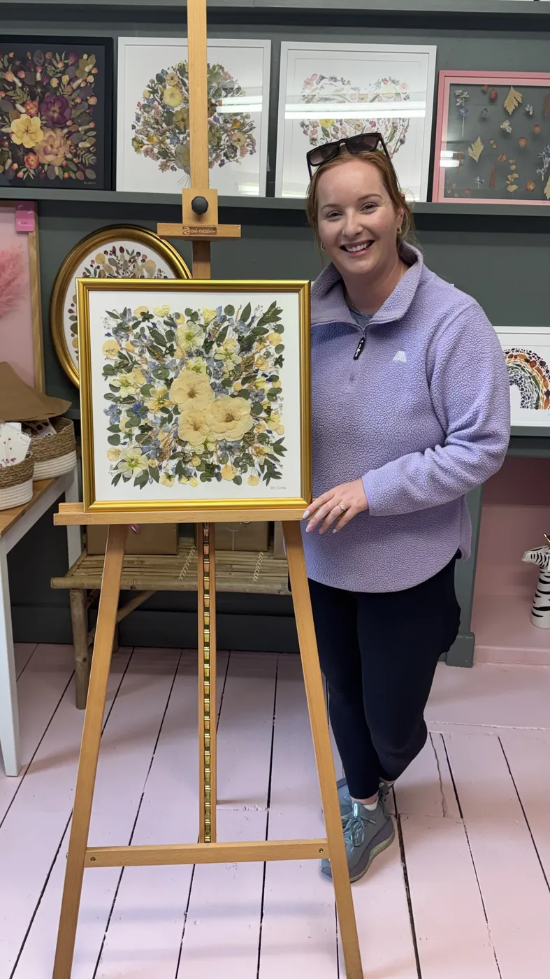A happy bride with her framed pressed wedding bouquet