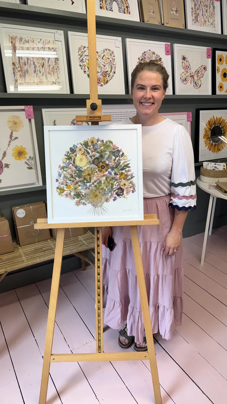 A happy bride with her framed pressed wedding bouquet