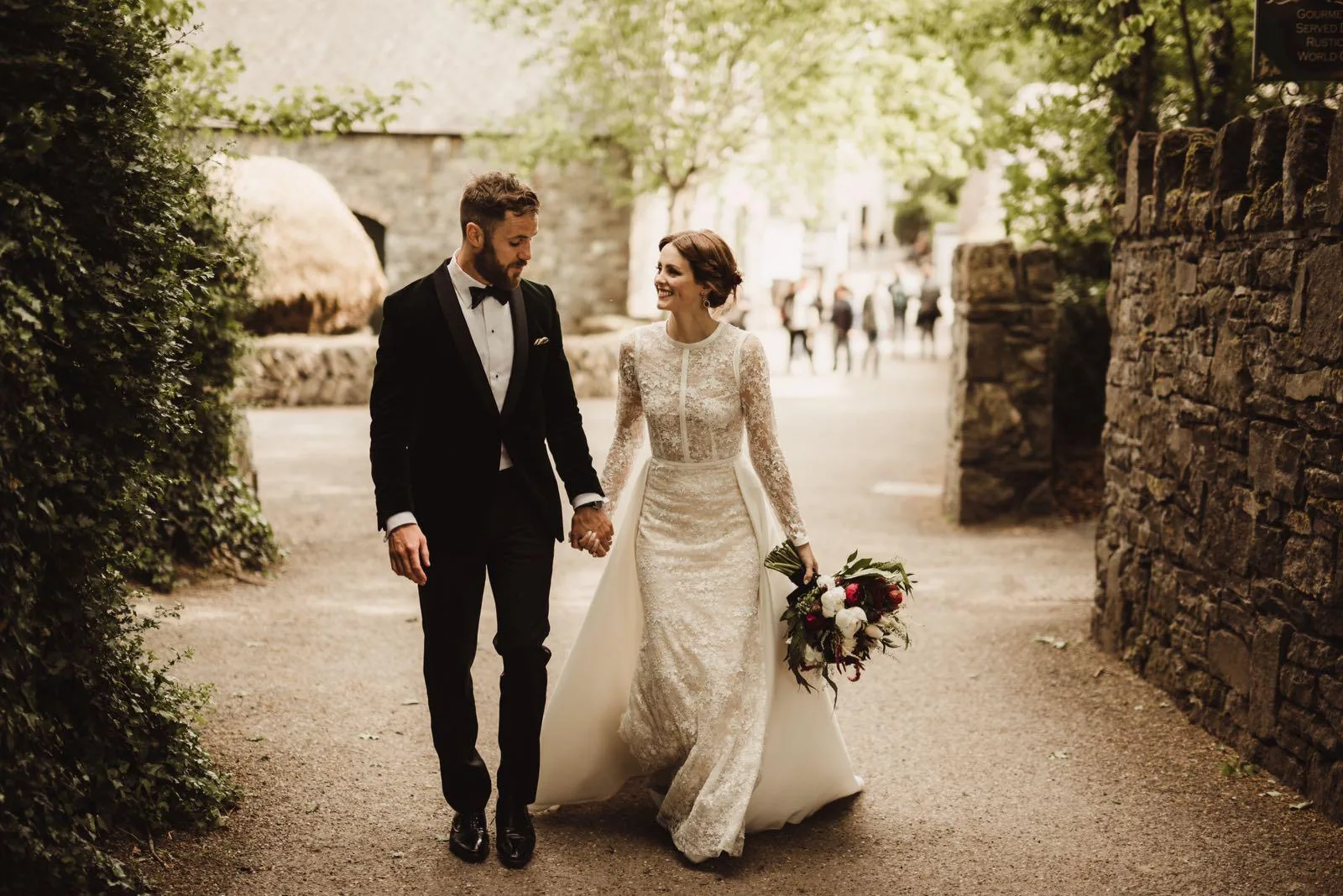 A bride and groom walking hand in hand, her bouquet in her hand
